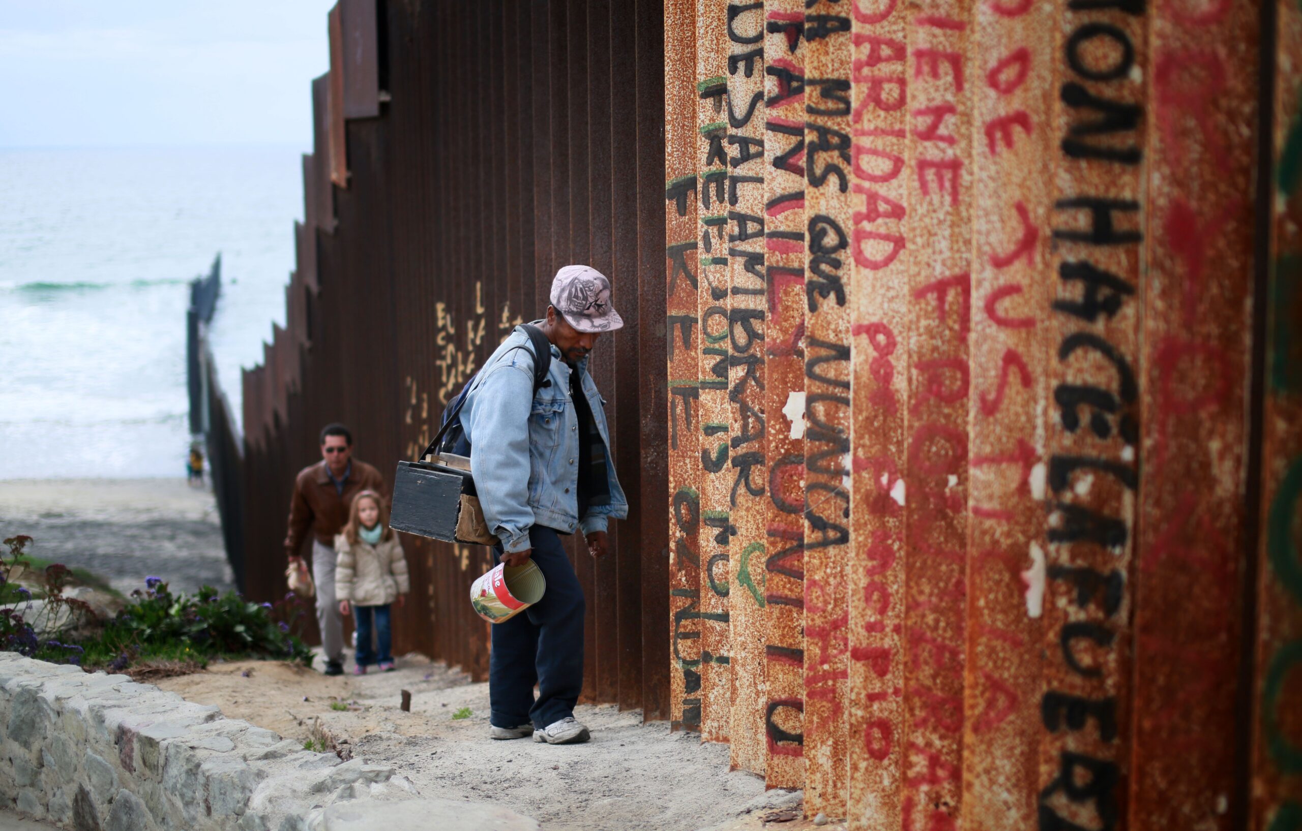 Migrantes en el muro fronterizo